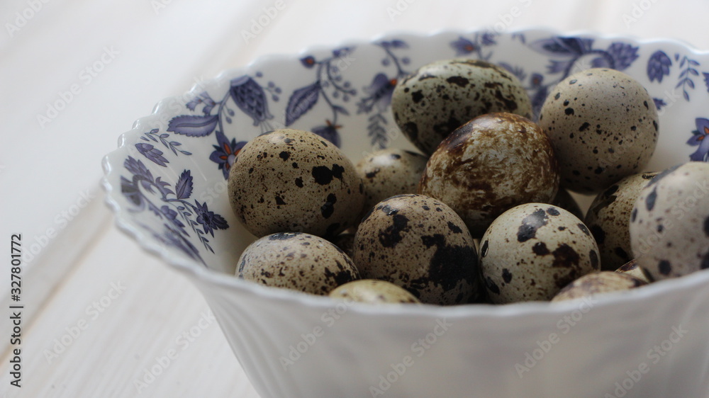 quail eggs in speck in a deep white bowl with blue ornament close-up quail eggs in speck in a deep white bowl with blue ornament close-up