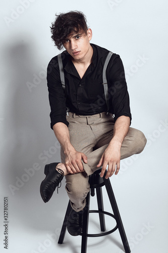 Young guy in a black shirt similar to Adriano Celentano posing on a white background. Fashion portrait photo