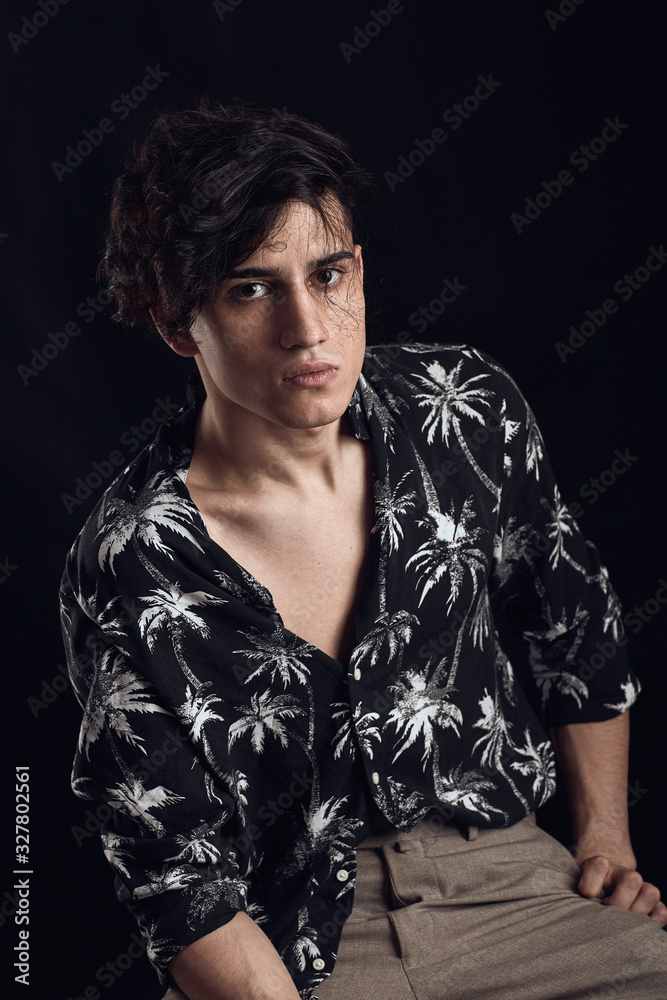 Young guy in a black shirt similar to Adriano Celentano posing on a black background. Fashion portrait Young guy in a black shirt similar to Adriano Celentano posing on a black background. Fashion portrait