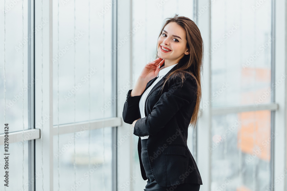 Cheerful female stands looking in the window, in her new office expressing pleasant emotions and confidence. Cheerful female stands looking in the window, in her new office expressing pleasant emotions and confidence.