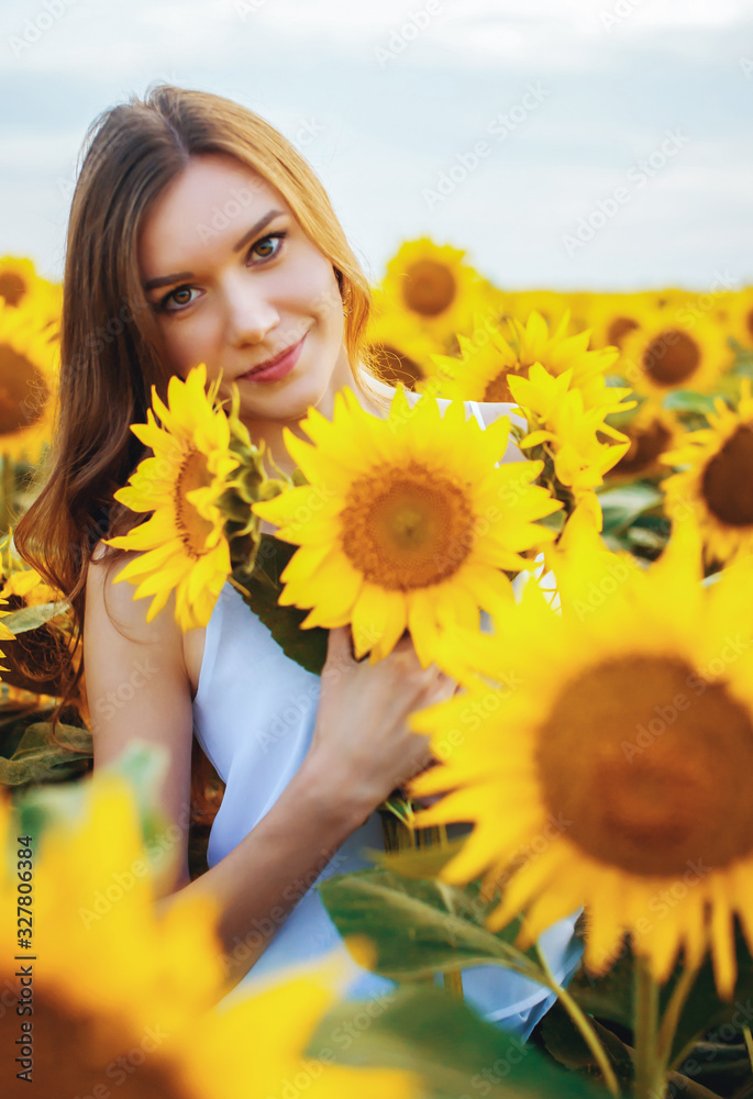 Beautiful young slender girl with long hair in a field with blooming sunflowers at sunset Beautiful young slender girl with long hair in a field with blooming sunflowers at sunset