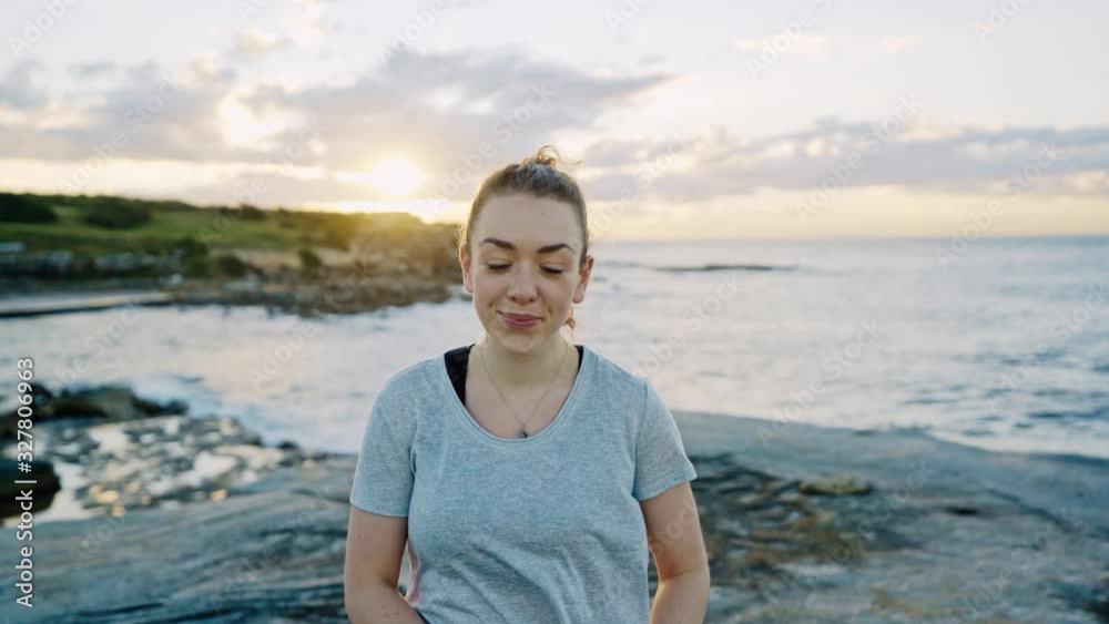 Pretty young woman walks towards the camera as the sunrise peaks over the cliffs at Clovelly in Sydney, Australia. Pretty young woman walks towards the camera as the sunrise peaks over the cliffs at Clovelly in Sydney, Australia.
