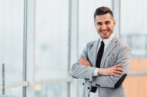 Vászonkép Confident young businessman standing with his hands folded, looking at the camera, ready to hard work day