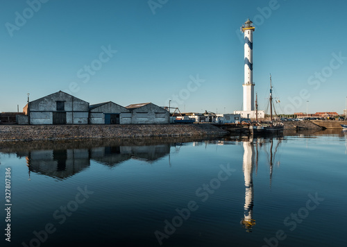 Old lighthouse of Ostend known as ‘Lange Nelle’, reflected in a commercial dock, Thursday 2 August 2018, Oostende, Belgium photo
