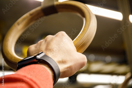 Young athlete with gymnastic dip rings in the gym. Focus on crossfit rings.