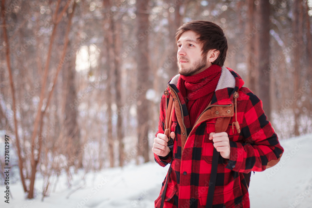 Male tourist with backpack walks on snow pine forest. Guy hiking at nature. Concept of winter holiday or vacation..