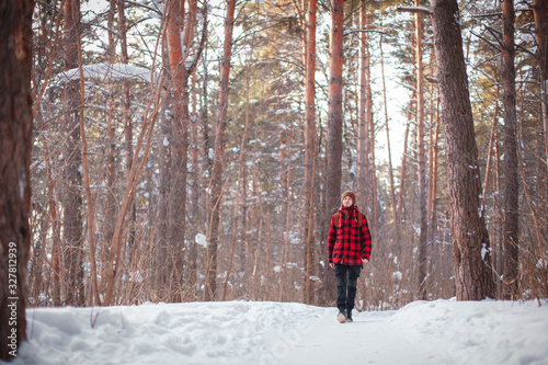 Male tourist with backpack walks on snow pine forest. Guy hiking at nature. Concept of winter holiday or vacation..