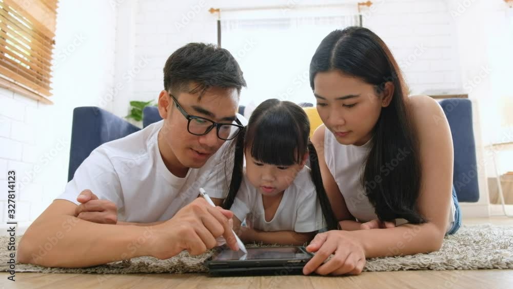 Happy Asian family using tablet, laptop, phone for playing game watching movies, relaxing at home for technology lifestyle concept