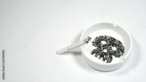 Image skull from ash inside ashtray. Smoldering cigarette on ashtray. photo