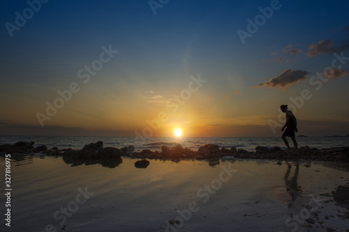 Sillouhuette of a man with amazing golden sunset view at the beach.Image contain noise due to High ISO shot.Soft focus image due to slow shutter shot.