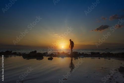 Sillouhuette of a man with amazing golden sunset view at the beach.Image contain noise due to High ISO shot.Soft focus image due to slow shutter shot.
