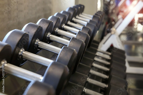 Motivation for Sport. Dumbbell sets in the gym. Sports equipment on a gymnasium background. Side view. Selective focus.