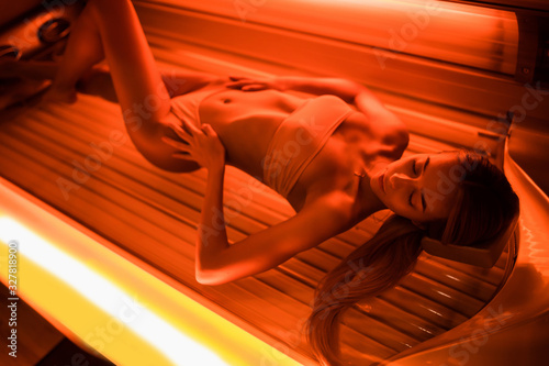Foto Beautiful young woman tanning skin treatment in modern solarium