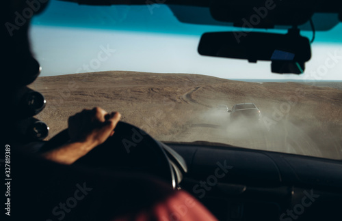 Evening dynamic landscape through the windshield of the car. Dusty village road with several cars. Road trip