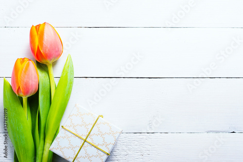 white gift box with tulip flowers on bright wood table #327821919