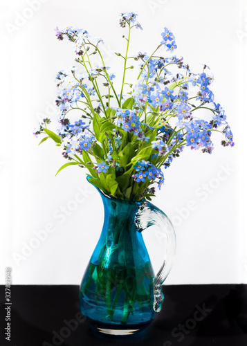 Blue forget-me-not flowers in a glass vase on a white background