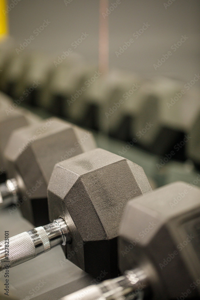 Rows of black dumbbells in the workout gym in high resolution and urban style.