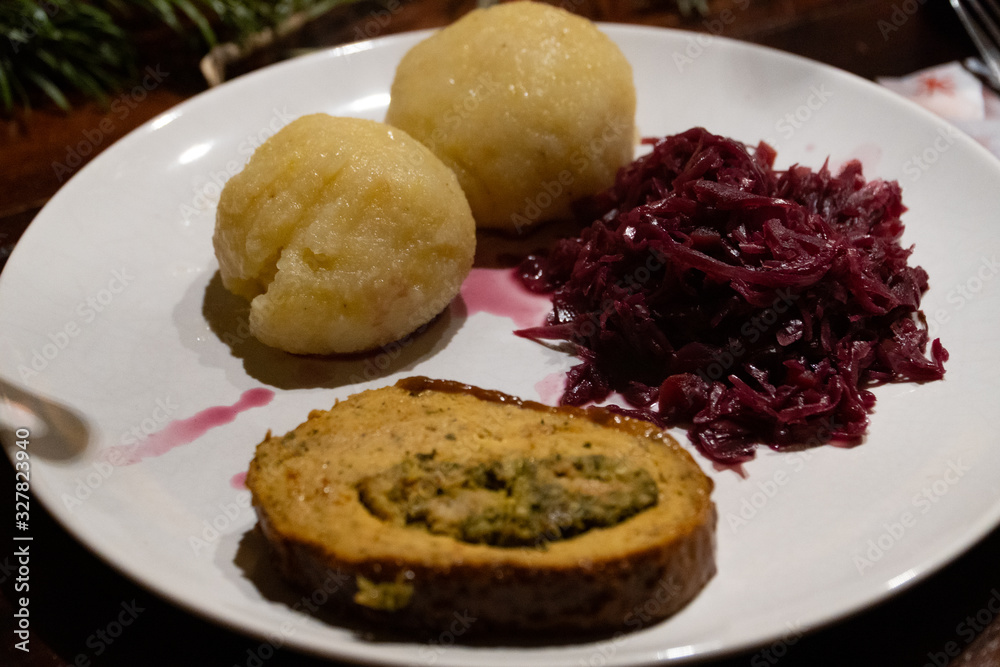 Close up of a plate with two dumplings, red cabbage and a roast - Vegan Christmas dinner