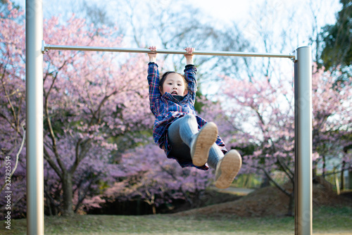 桜が咲く公園で鉄棒をする女の子