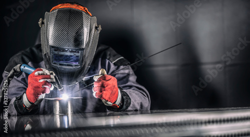 Welder industrial worker welding with argon machine photo