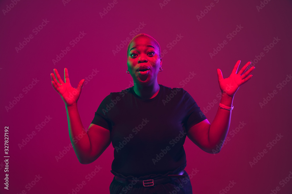 Astonished, shocked. African-american young woman's portrait on purple background. Beautiful model in black shirt. Concept of emotions, facial expression, sales, ad, inclusion, diversity. Copyspace.