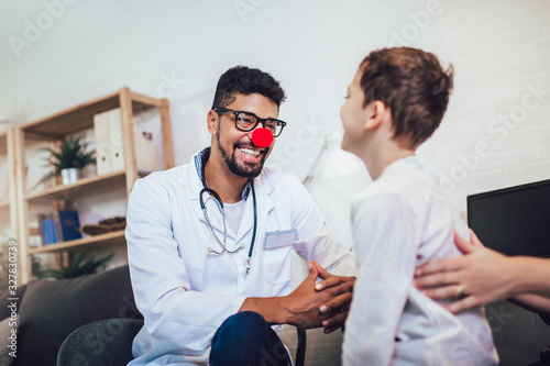 African American male pediatrician with stethoscope and clown nose talking to little boy