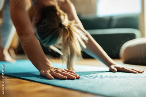 Close-up of woman stretching while practicing Yoga at home.
