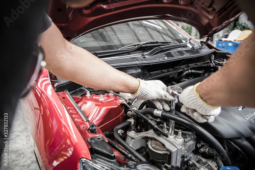 Hand of auto mechanic doing car service and maintenance.