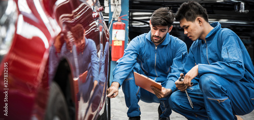 Two auto mechanic doing car service and maintenance.