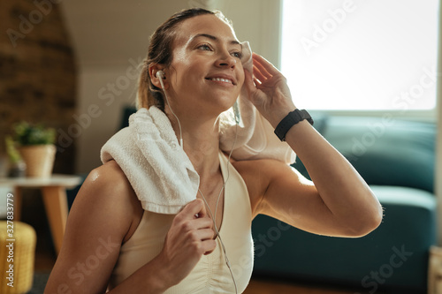 Fototapeta Naklejka Na Ścianę i Meble -  Young happy sportswoman wiping sweat with a towel on a break at home.