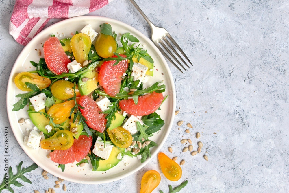 Avocado salad with grapefruits, tomato, feta cheese, arugula and sunflower seeds. Top view with copy space. Avocado salad with grapefruits, tomato, feta cheese, arugula and sunflower seeds. Top view with copy space.