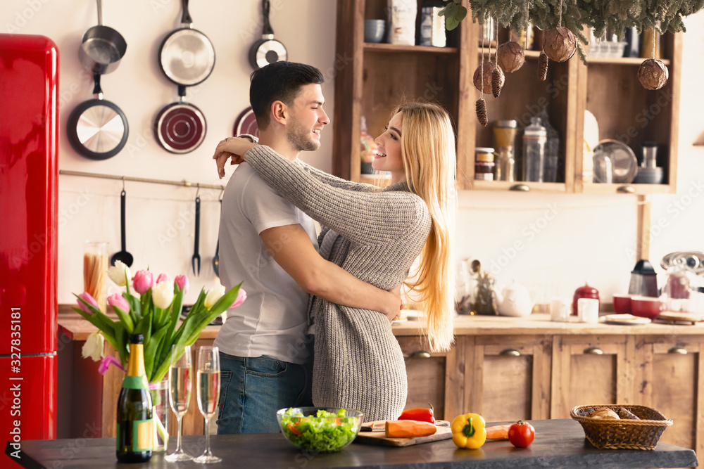 Young couple hugging while cooking breakfast together in kitchen