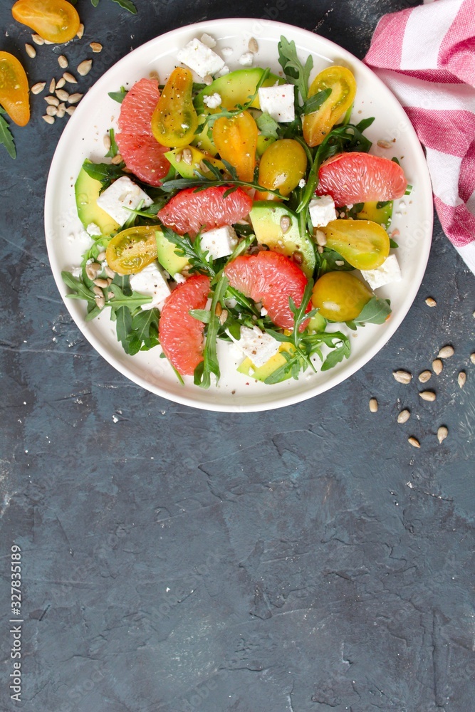 Avocado salad with grapefruits, tomato, feta cheese, arugula and sunflower seeds. Top view with copy space. Avocado salad with grapefruits, tomato, feta cheese, arugula and sunflower seeds. Top view with copy space.