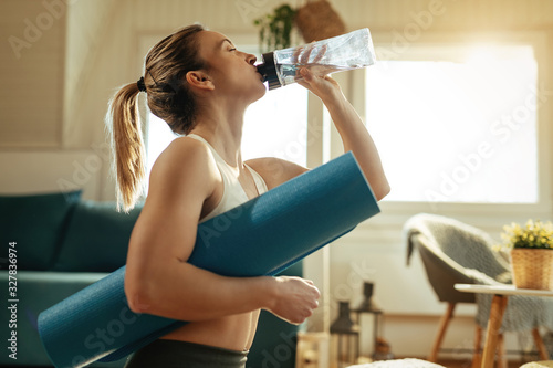 Side view of athletic woman drinking fresh water after sports training.