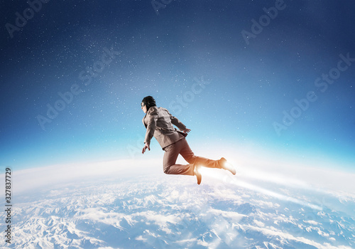 Businessman in suit and aviator hat flying in sky