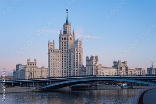 View of illuminated Stalin skyscraper on the Kotelnicheskaya embankment and Moscow River at evening
