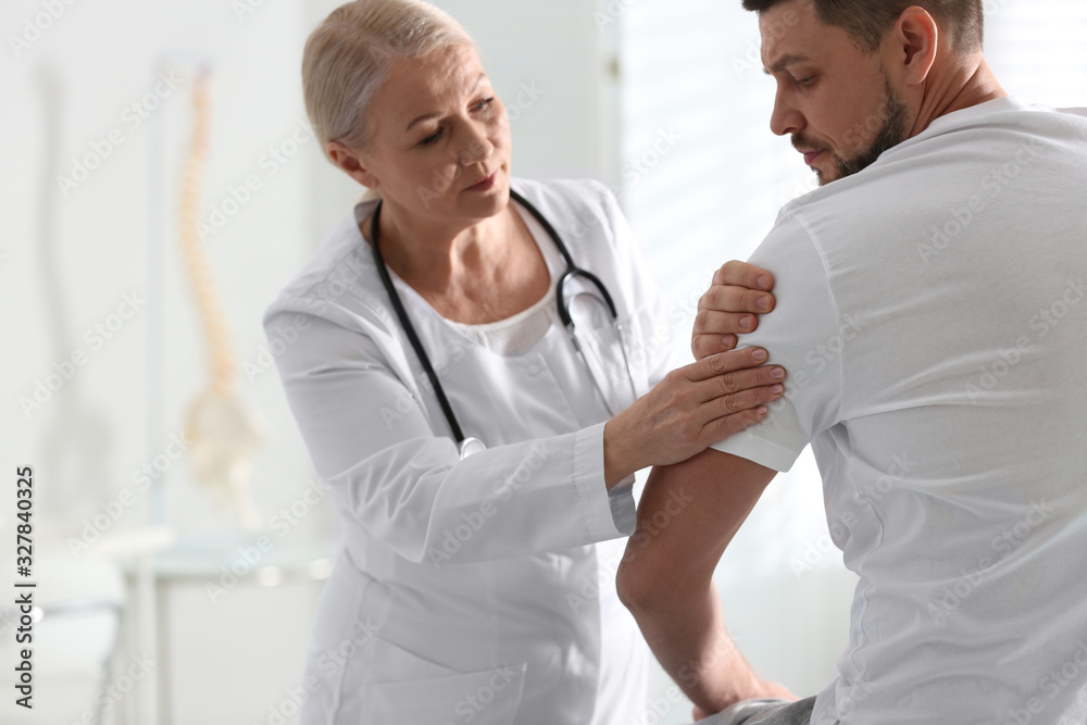 Fototapeta premium Male orthopedist examining patient's arm in clinic