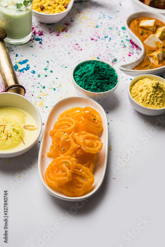 Happy Holy concept  showing Indian assorted lunch food like chicken, paneer butter masala, naan, jeera rice, black chana fry, jalebi, fujiyama, thandai and Farsan with holi colours and pichkari  photo