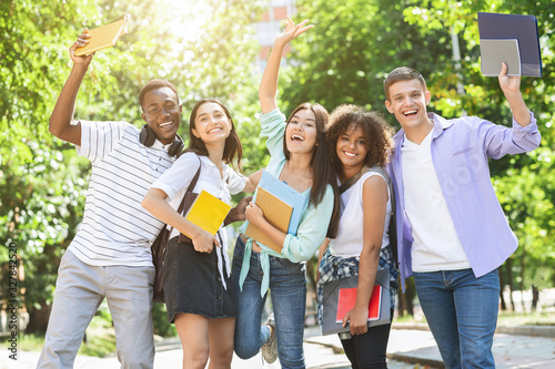 Portrait of joyful college students posing outdoors after passing exam