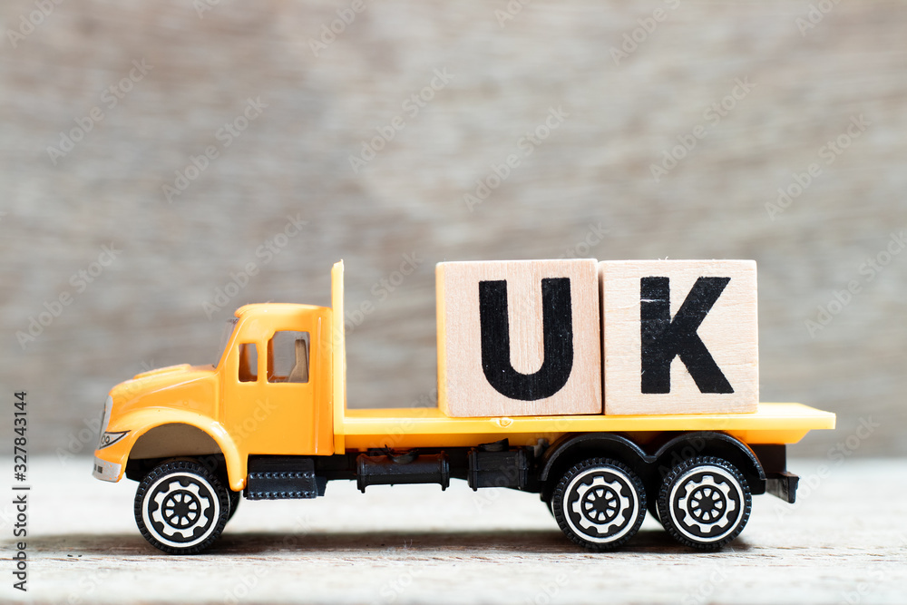 Truck hold letter block in word UK (abbreviation of united kingdom) on wood background - obrazy, fototapety, plakaty 