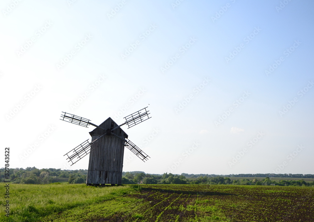 old wooden four-bladed windmill in a field at summer old wooden four-bladed windmill in a field at summer