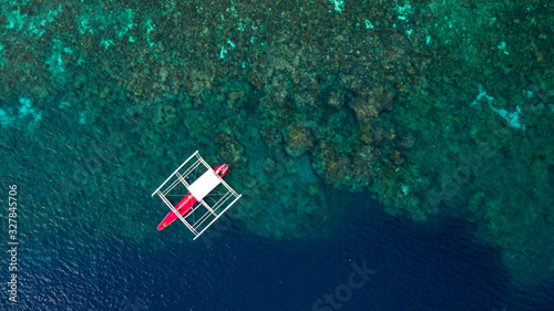Aerial top down view of boat moving in open sea with clear and turquoise water on over coral reef,  Boat left the tropical lagoon, Moalboal, Oslob, Cebu Island, Philippines. © Kalyakan
