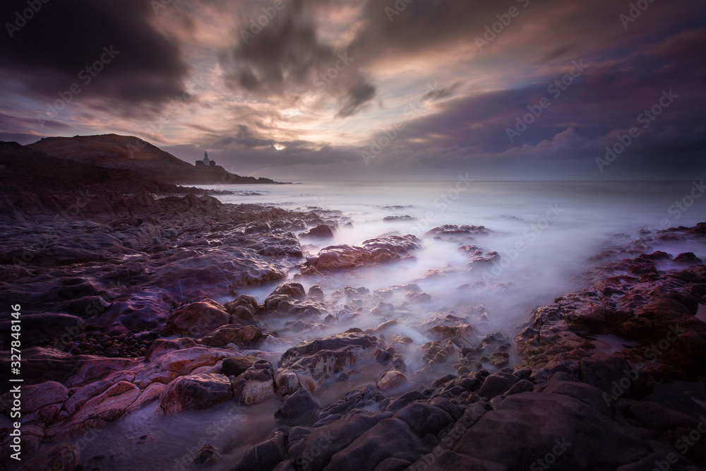 Daybreak over Bracelet Bay with a long exposure over the rock pools on the Gower peninsula in Swansea, South Wales, UK