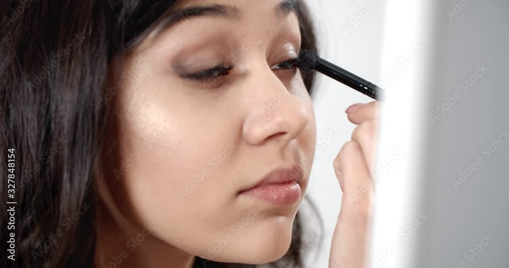 Pretty brunette woman doing eyes makeup using eye shadows and brush, glamour