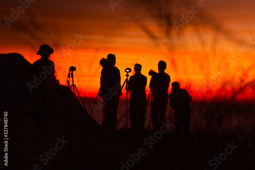 Silhouette of group tourists take a photo on a hill at sunset