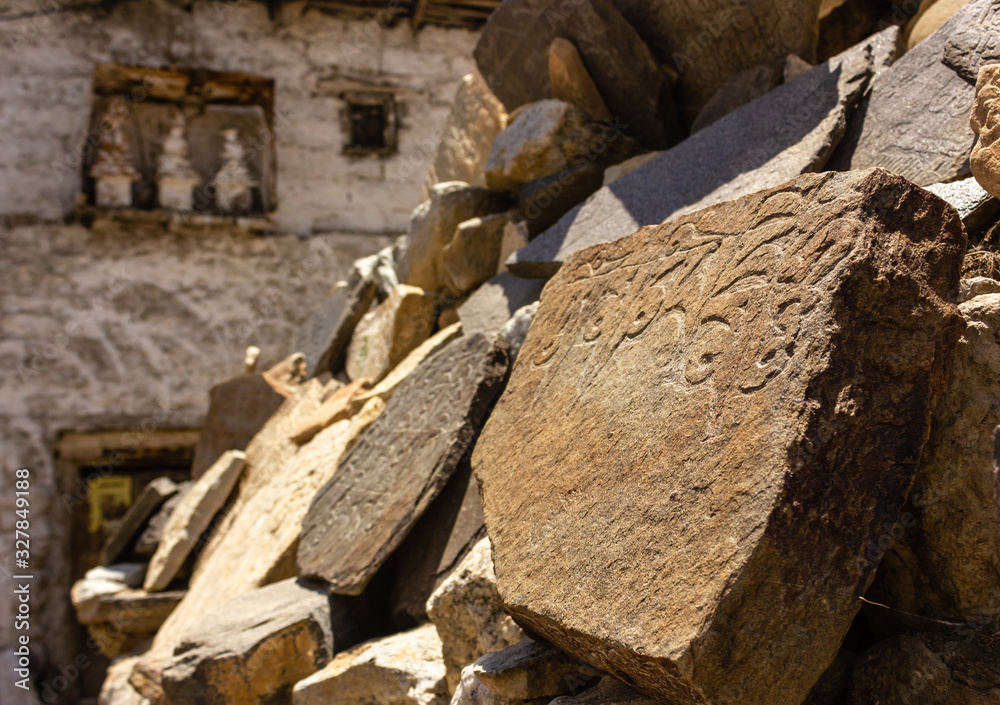 Fototapeta premium An old mani stone with Tibetan prayers scrawled on it outside an ancient Buddhist monastery in the village of Nako in Kinnaur, India.