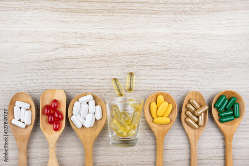 Medicine, vitamins and antioxidant supplements in wood spoon on table