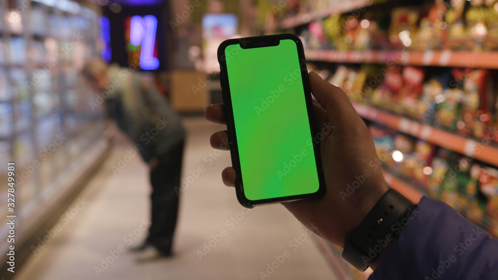 Lviv, Ukraine - May 19, 2018: On shop man hands holding use touch phone with horizontal green screen background busy finger touch message cellphone display girl slow motion
