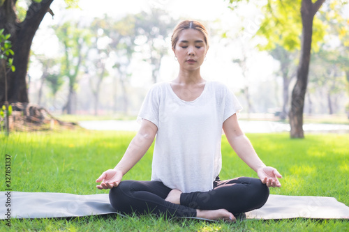 Portrait of young woman practicing yoga in garden.female happiness. blurred background.Healthy lifestyle and relaxation concept.Young Asian Girl doing yoga in the park