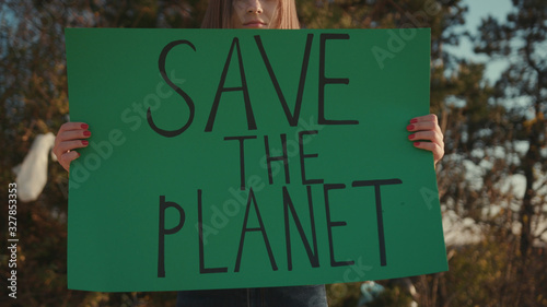 Close up hands woman activist holding encouraging green poster Save the Planet standing at landfill site with garbage nature environmental community earth eco environment outdoor recycle trash waste photo